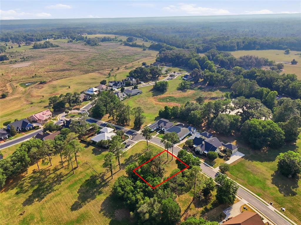 An aerial view shows a vacant, tree-covered lot outlined in red within a residential neighborhood — 6713 SW 40TH TERRACE, GAINESVILLE, FL