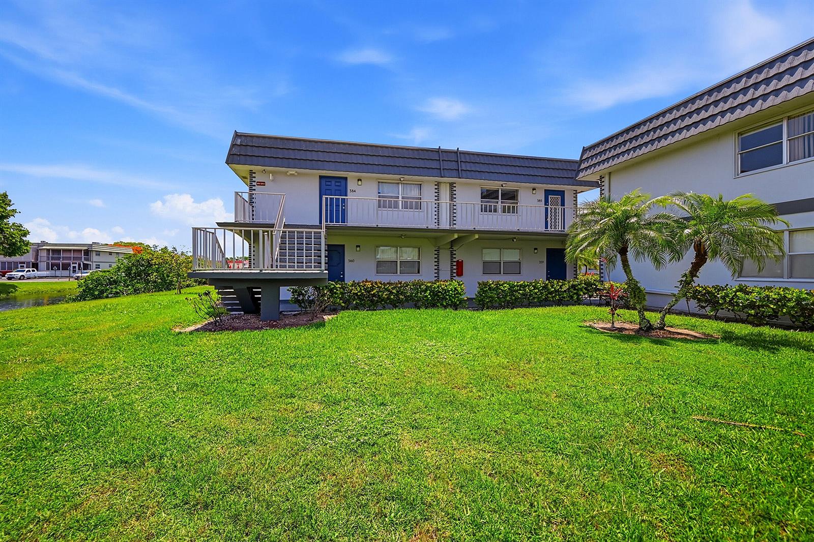 A two-story apartment building exterior with a metal staircase, balconies, and a grassy lawn — 383 Saxony Lane # H, Delray Beach FL 33446, DELRAY BEACH, FL