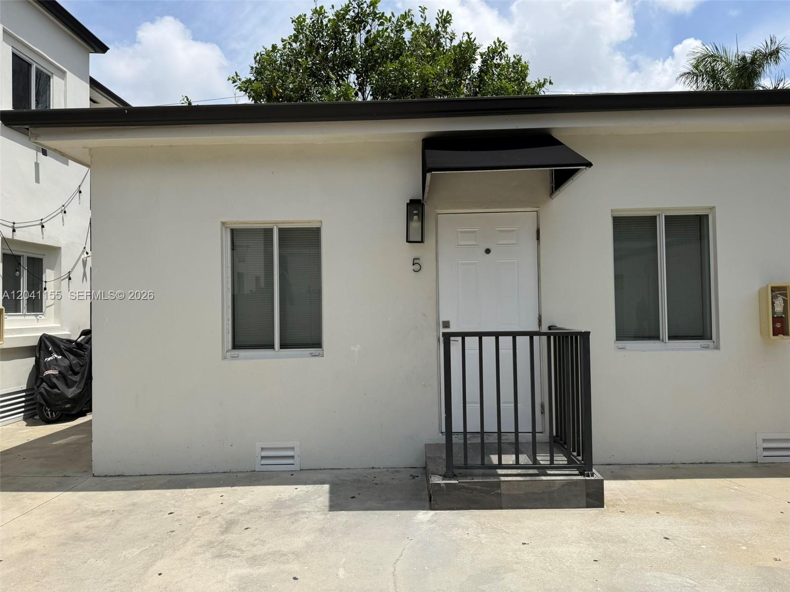 A white exterior wall features a central door with a black awning and metal railing — 111 SW 11 Ave # 5, Miami FL 33130, MIAMI, FL