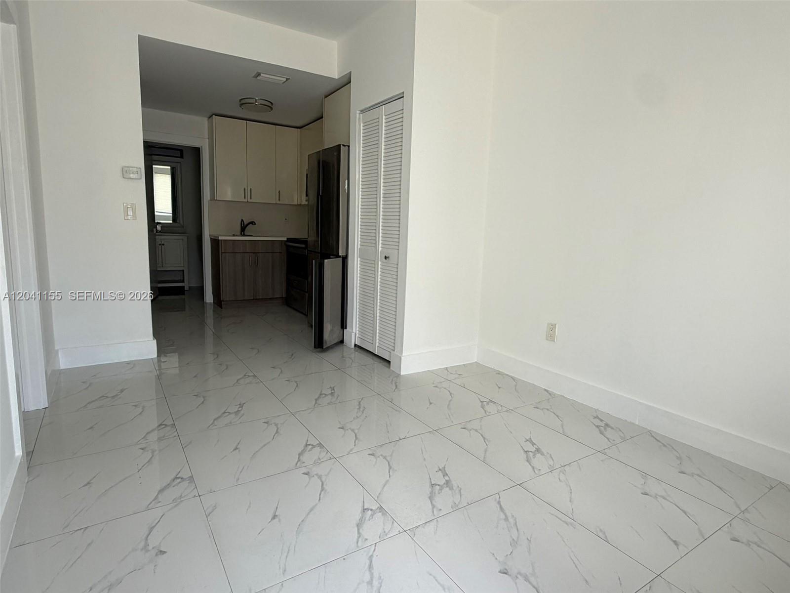 A kitchen with stainless steel appliances and white cabinets opens into a tiled living area — 111 SW 11 Ave # 5, Miami FL 33130, MIAMI, FL