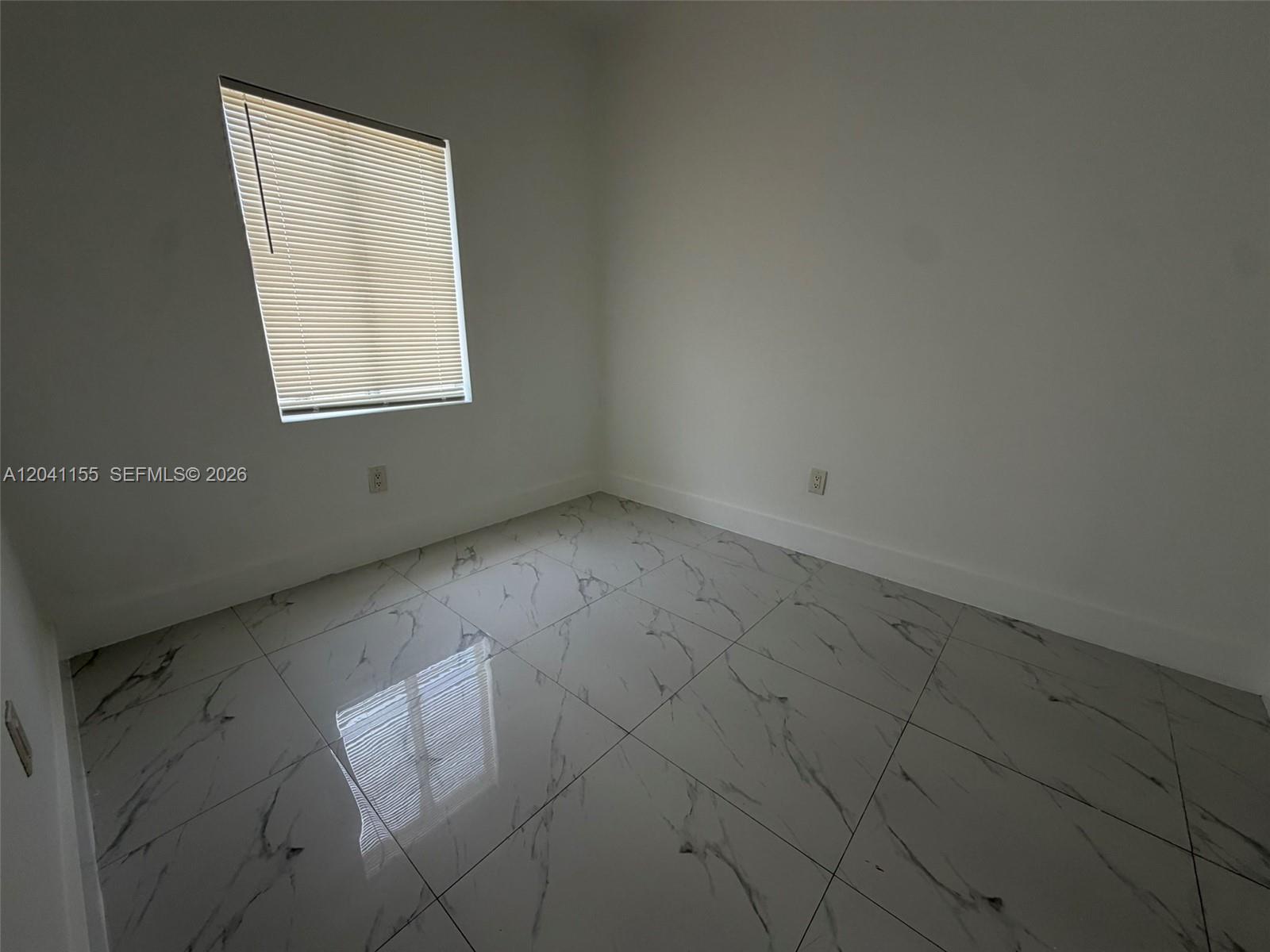 An empty room features white walls, a window with blinds, and white marble-patterned tile flooring — 111 SW 11 Ave # 5, Miami FL 33130, MIAMI, FL