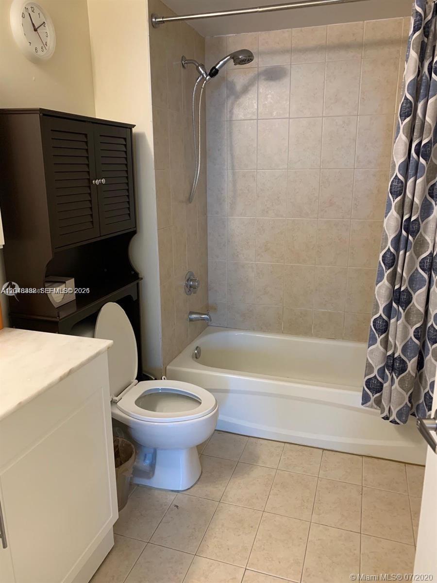 A bathroom features a white toilet, a dark wood storage unit, and a tiled shower-tub — 275 NE 18th St # 1109, Miami FL 33132, MIAMI, FL