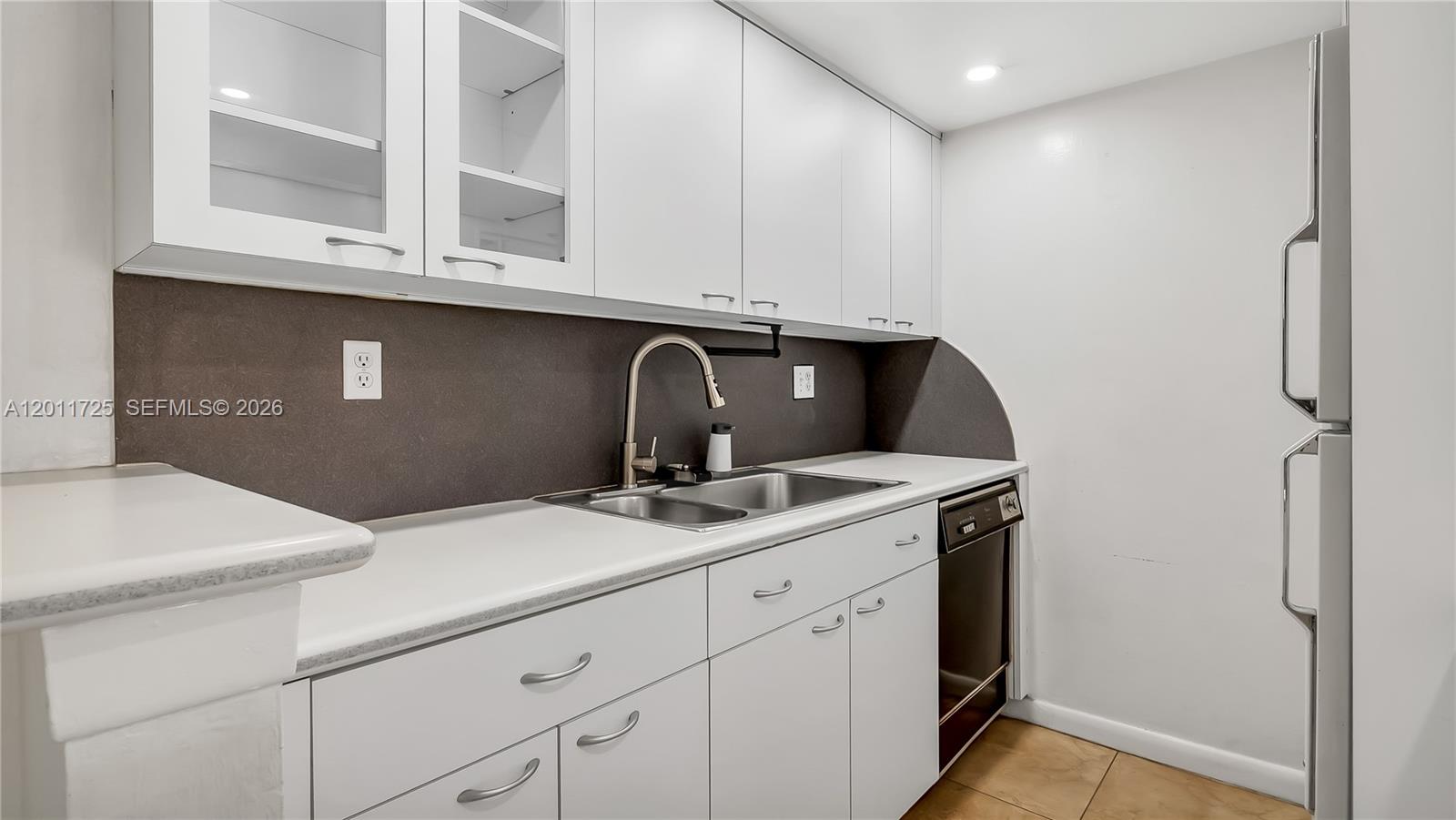 A kitchen features white cabinets, a dark backsplash, a stainless steel sink, and a refrigerator — 7200 Fairway Dr # H12, Miami Lakes FL 33014, MIAMI LAKES, FL