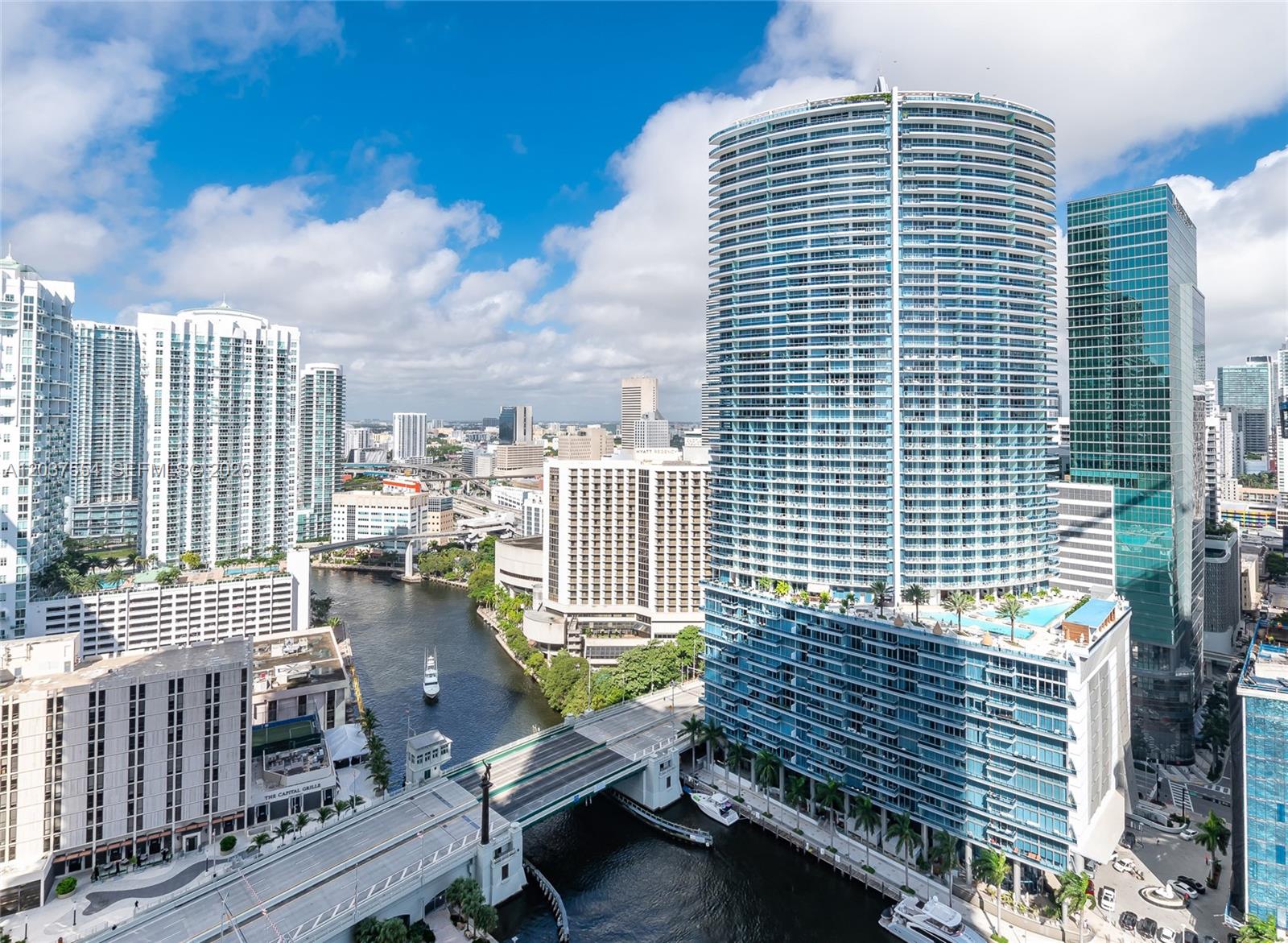 An aerial view of a city skyline featuring a tall cylindrical skyscraper beside a river — 475 Brickell Ave # 2908, Miami FL 33131, MIAMI, FL