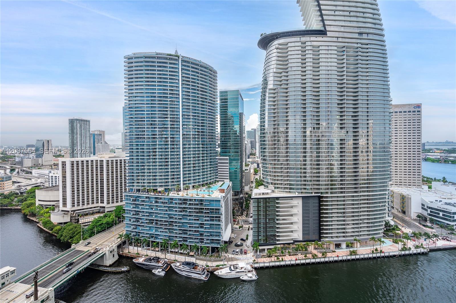 An aerial view of high-rise buildings along a river with docked yachts and a bridge — 475 Brickell Ave # 2908, Miami FL 33131, MIAMI, FL