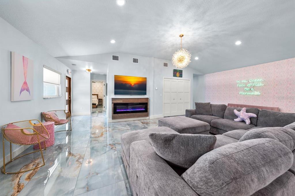 A living room features a grey sectional sofa, a fireplace with a television, and tiled floors — 2050 W BAY DRIVE, LARGO, FL