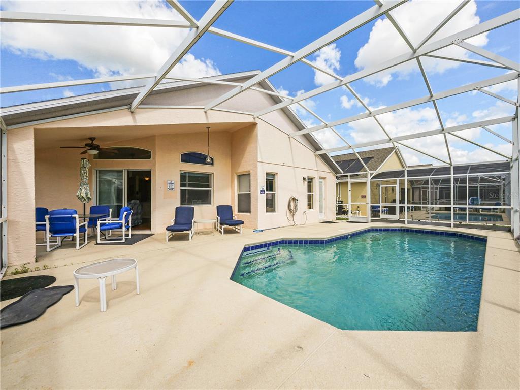 A swimming pool sits on a patio enclosed by a screened-in lanai behind a house — 160 HIGH POINT DRIVE, DAVENPORT, FL