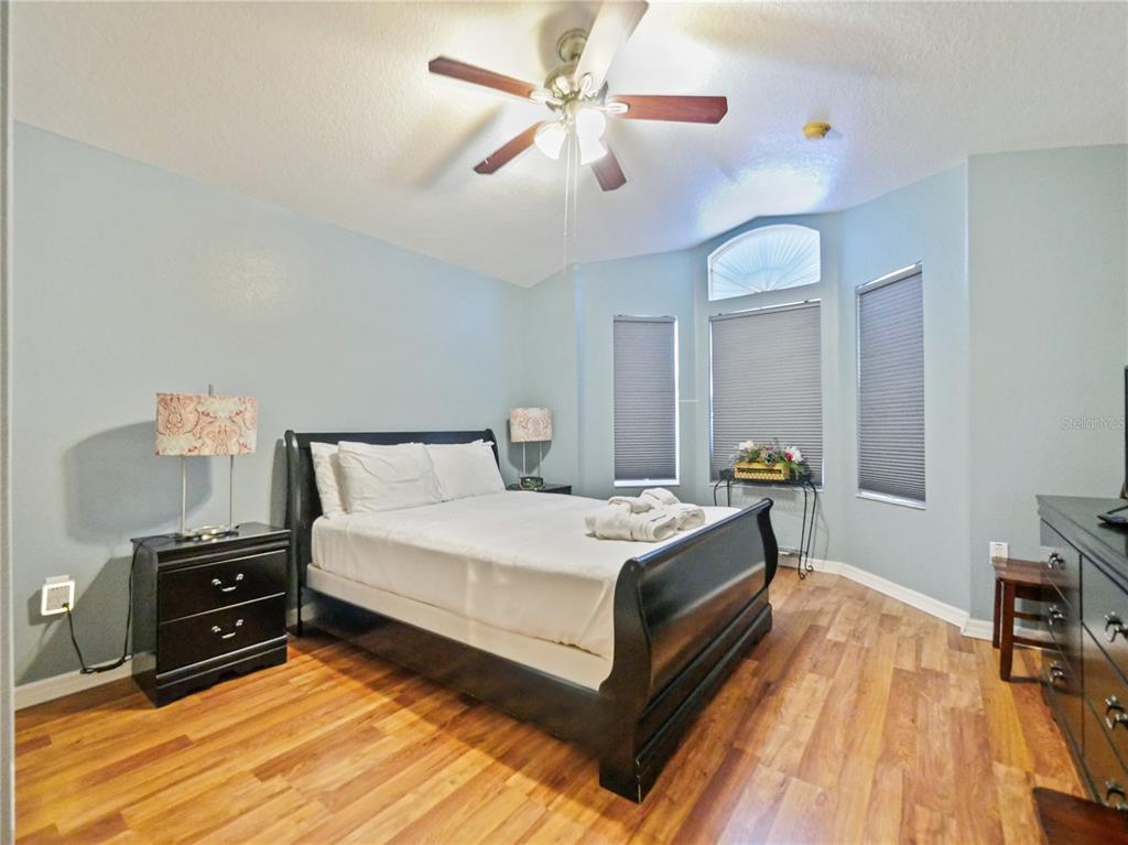 A bedroom features a dark wood sleigh bed, light blue walls, and wood-look flooring — 160 HIGH POINT DRIVE, DAVENPORT, FL