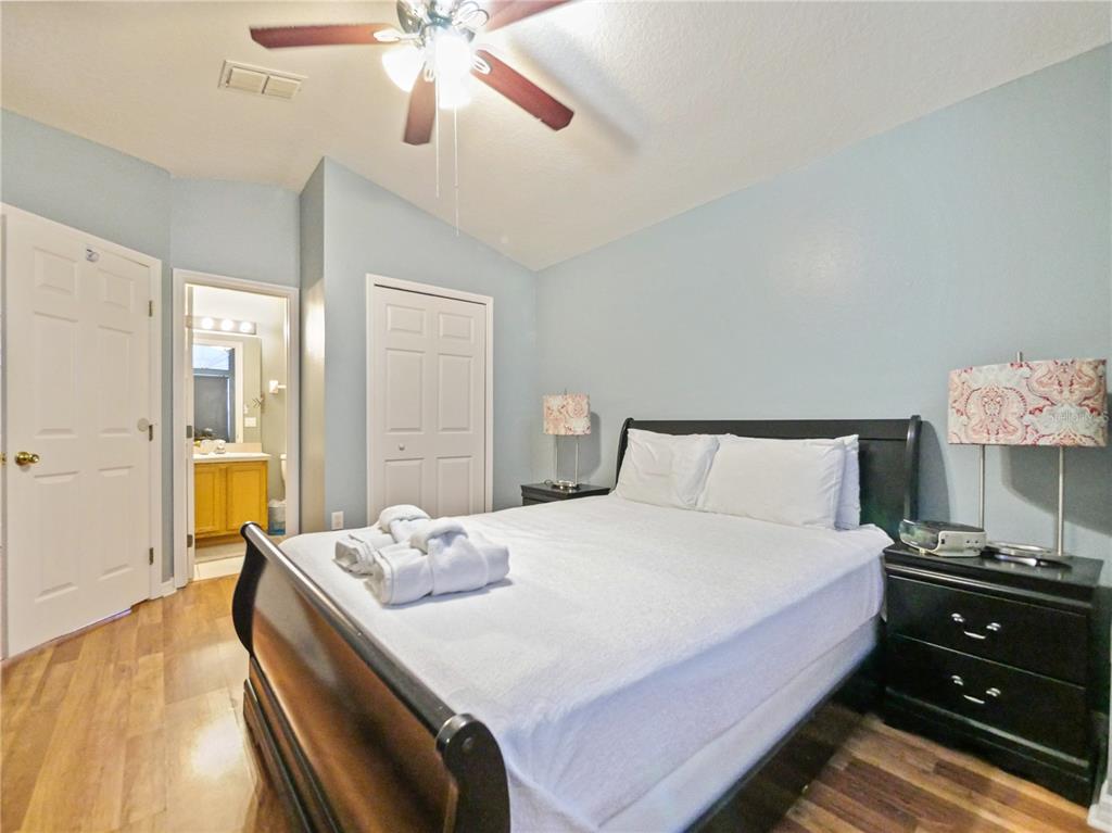 A bedroom features a dark wood bed frame, light blue walls, and wood-look flooring — 160 HIGH POINT DRIVE, DAVENPORT, FL