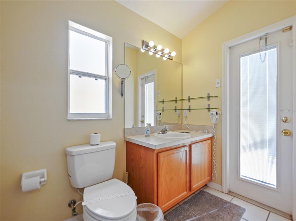 A bathroom features a wooden vanity, a toilet, a mirror, and a glass-paned door — 160 HIGH POINT DRIVE, DAVENPORT, FL