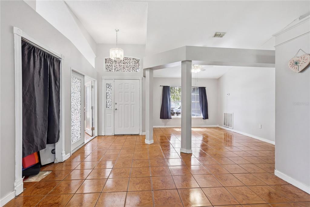 An entryway with brown tile flooring, white walls, and a decorative columned room divider — 725 W 9TH STREET, DELTONA, FL
