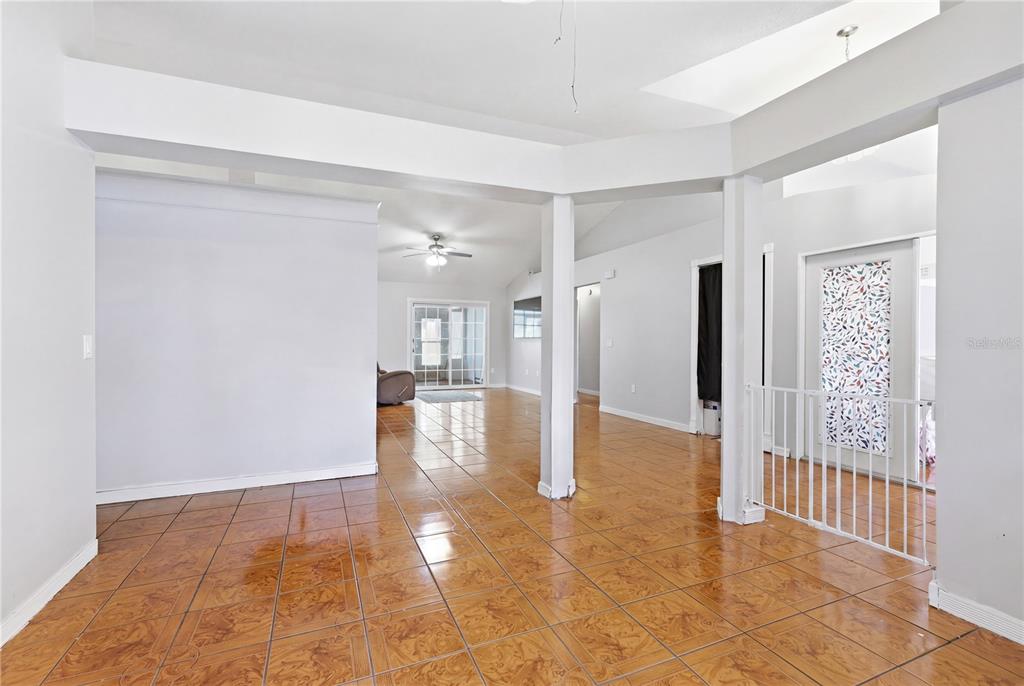 A spacious room features light gray walls, brown tiled flooring, and white support pillars — 725 W 9TH STREET, DELTONA, FL