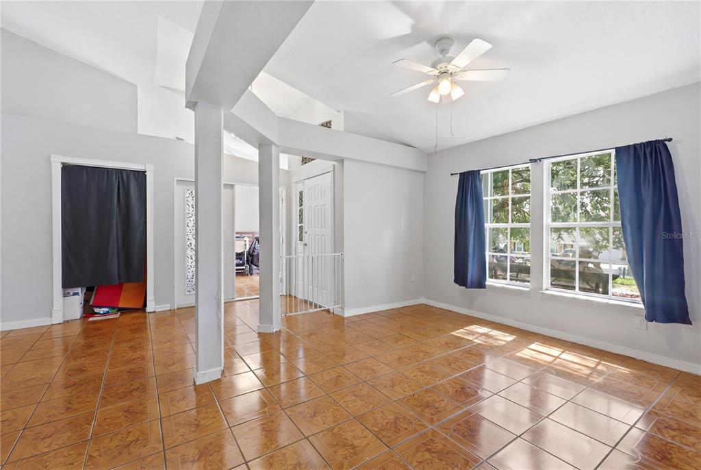A living room with light gray walls, brown tile flooring, and a white ceiling fan — 725 W 9TH STREET, DELTONA, FL