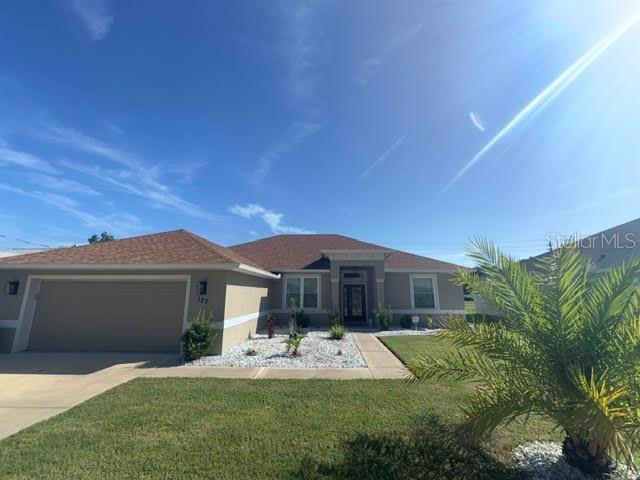A single-story house with a tan exterior, a two-car garage, and a palm tree — 123 BICKFORD DRIVE, PALM COAST, FL