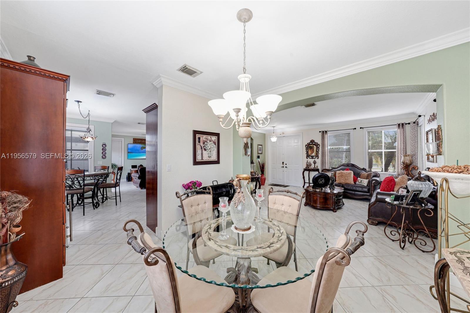 A dining area with a glass table and chandelier opens into a living room — 2250 SW 155th Ave, Miami FL 33185, MIAMI, FL