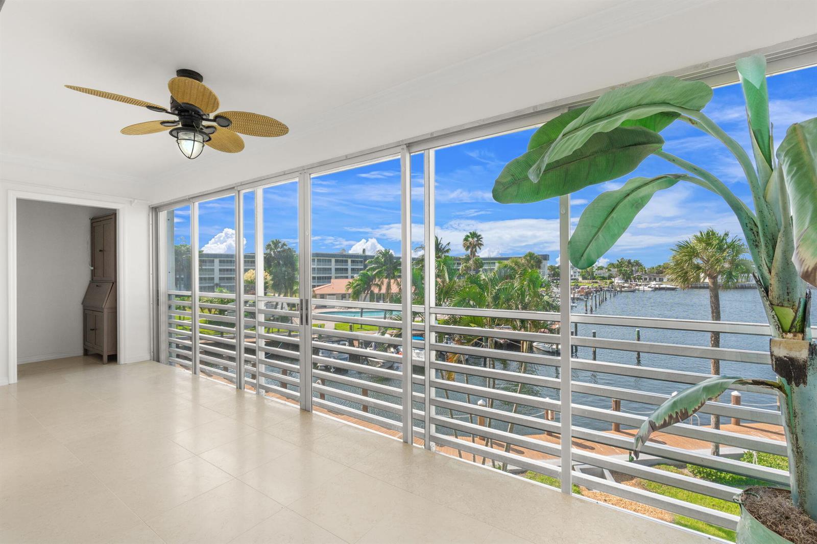 A sunroom with tile flooring, a ceiling fan, and sliding glass doors overlooking a waterway — 951 Spanish Circle # 346, Delray Beach FL 33483, DELRAY BEACH, FL
