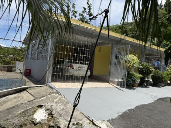 A single-story house with a gated carport and a paved driveway under a blue sky — Carr 900 PARCELAS NUEVAS, YABUCOA, PR