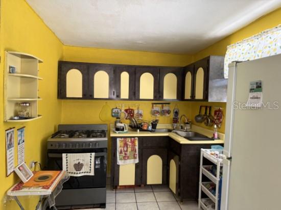 A kitchen with yellow walls, dark brown cabinets with arched panels, and a gas stove — Carr 900 PARCELAS NUEVAS, YABUCOA, PR