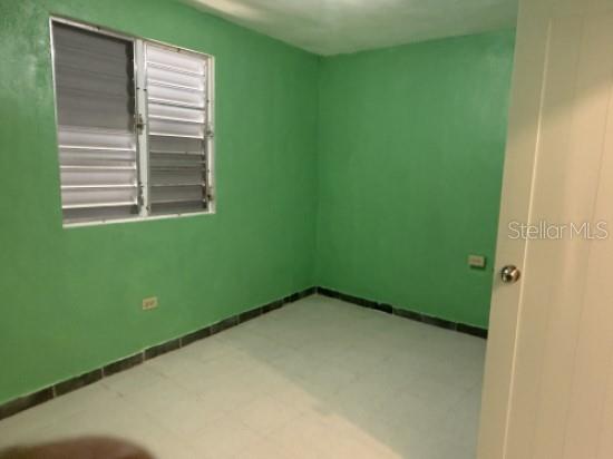 An empty room with green walls, a louvered window, and light-colored tile flooring — Carr 900 PARCELAS NUEVAS, YABUCOA, PR