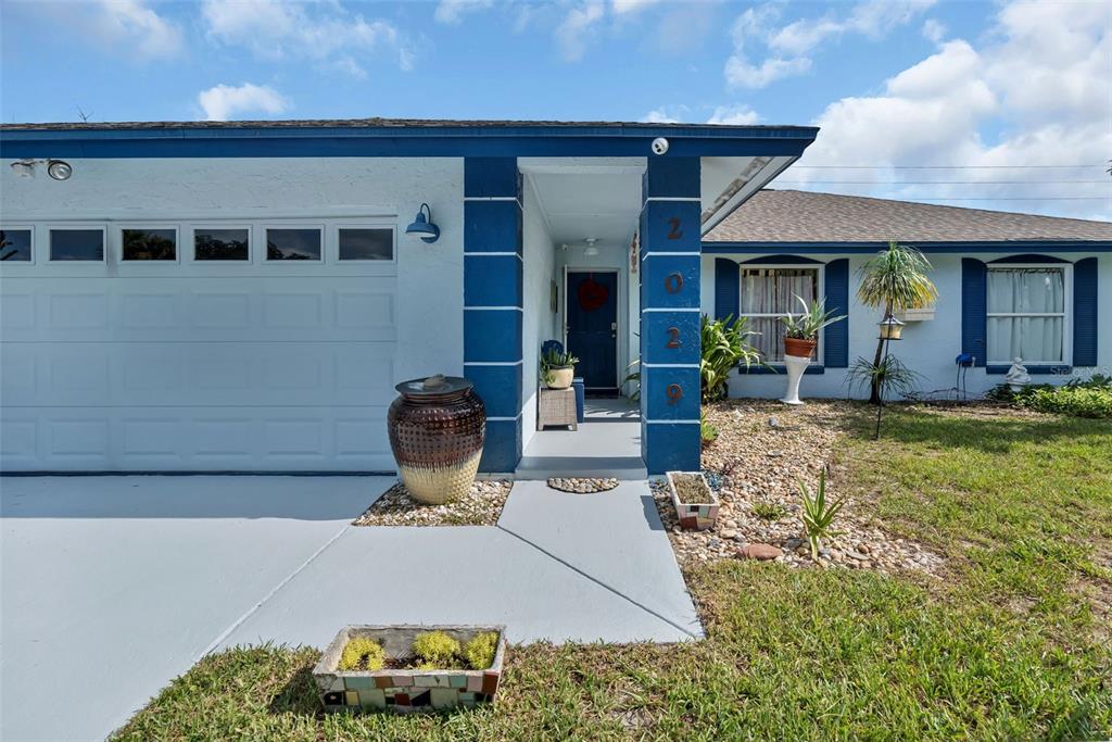 The exterior of a single-story house features a blue-trimmed entryway, garage, and landscaped yard — 2029 ALLSPICE AVENUE, ORLANDO, FL