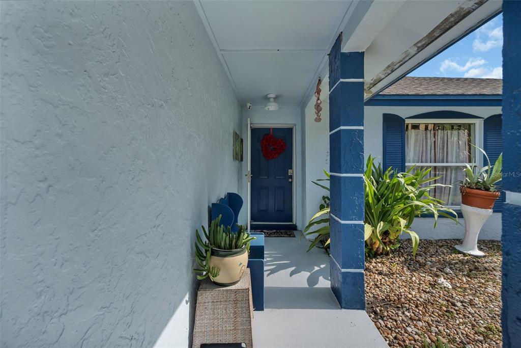 A covered front porch features a blue door, a textured light blue wall, and a pillar — 2029 ALLSPICE AVENUE, ORLANDO, FL