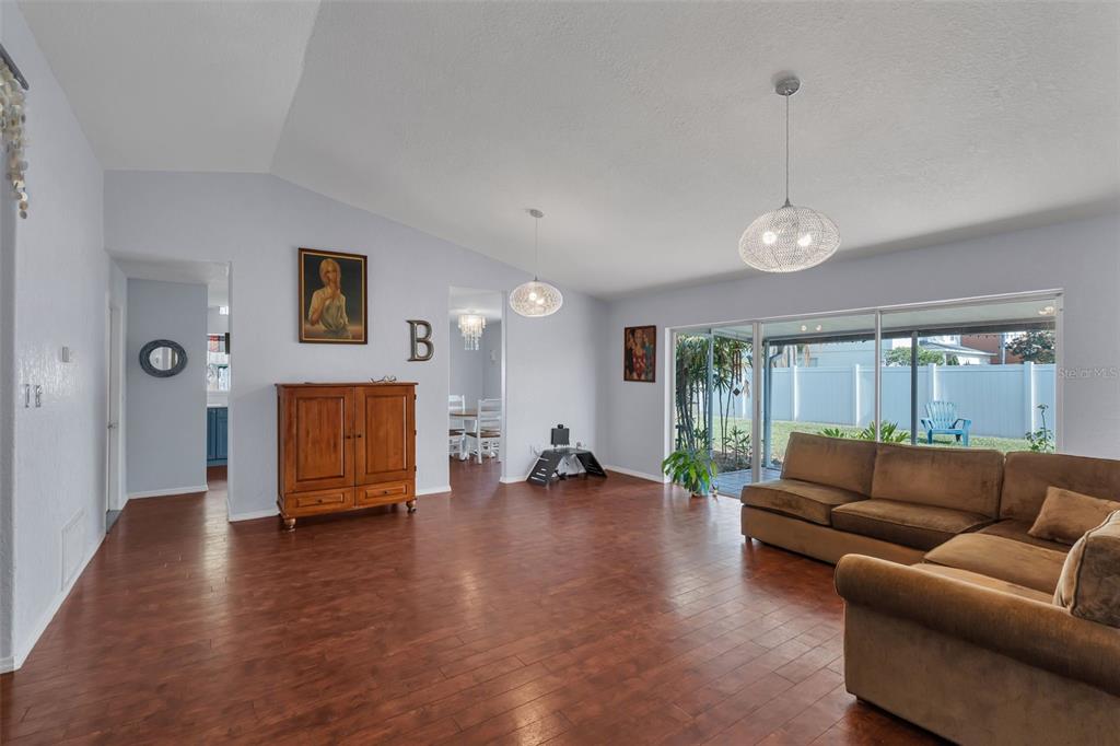 A living room with wood flooring, a brown sectional sofa, and two hanging pendant lights — 2029 ALLSPICE AVENUE, ORLANDO, FL