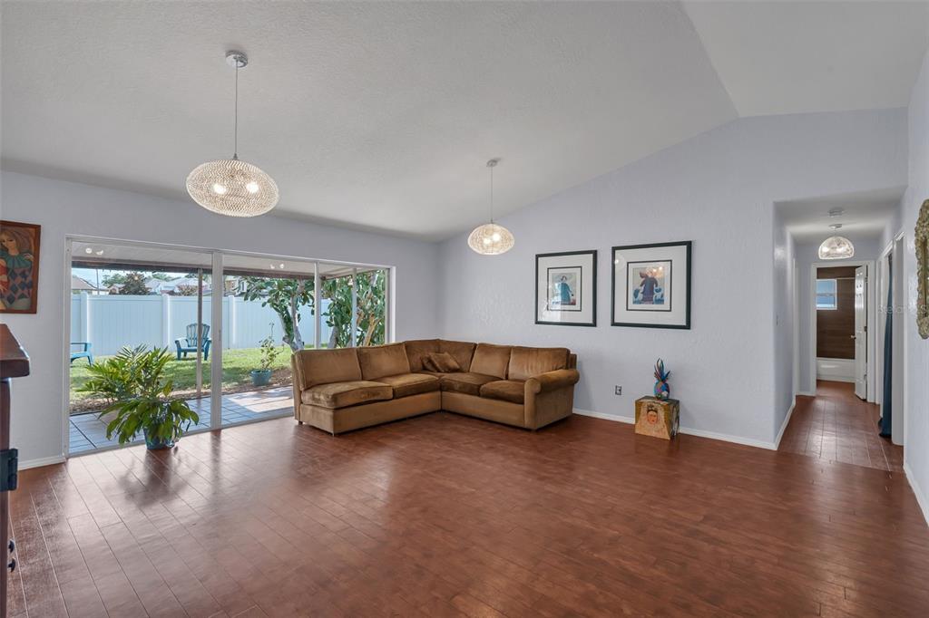 A living room with wood flooring, a brown sectional sofa, and sliding glass patio doors — 2029 ALLSPICE AVENUE, ORLANDO, FL