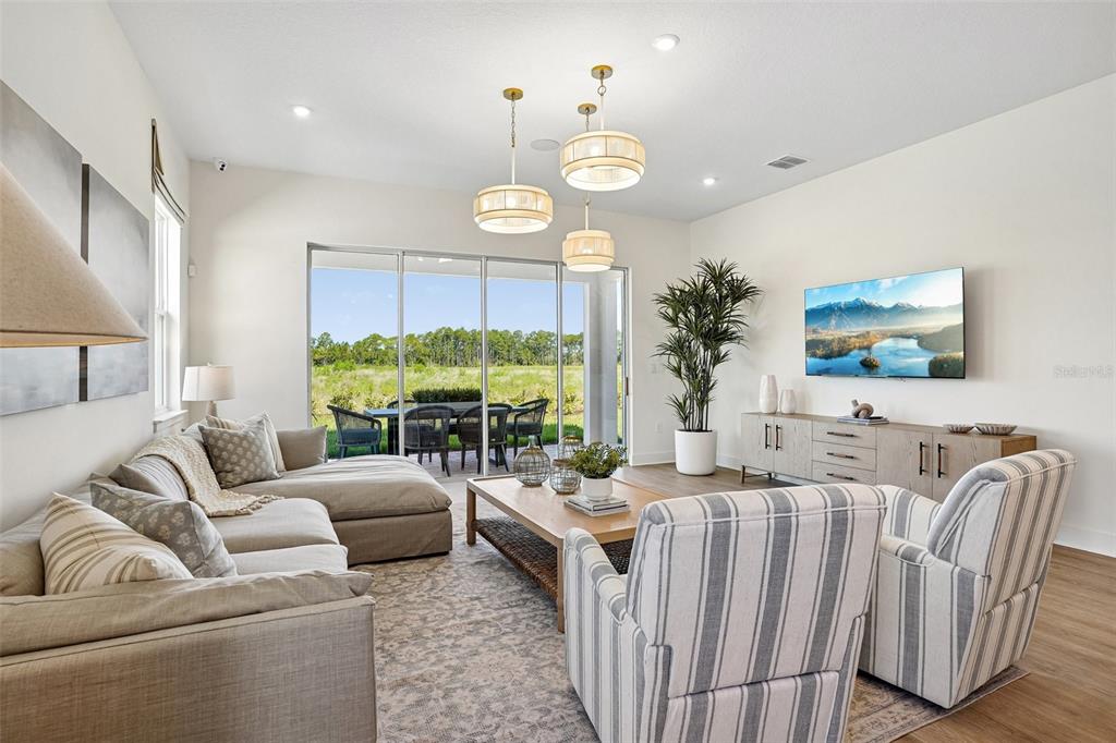 A living room features a sectional sofa, two striped armchairs, and sliding doors to a patio — 17406 HONEYBELL TANGELO COURT, WINTER GARDEN, FL