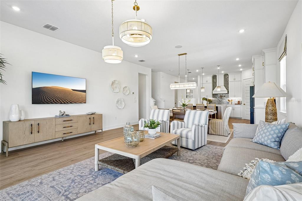 A bright, open-concept living and dining area features light wood floors, neutral furniture, and pendant lighting — 17406 HONEYBELL TANGELO COURT, WINTER GARDEN, FL