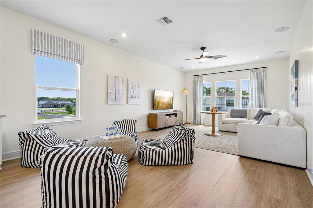 A living room features striped beanbag chairs, a white sectional sofa, and light wood flooring — 17406 HONEYBELL TANGELO COURT, WINTER GARDEN, FL
