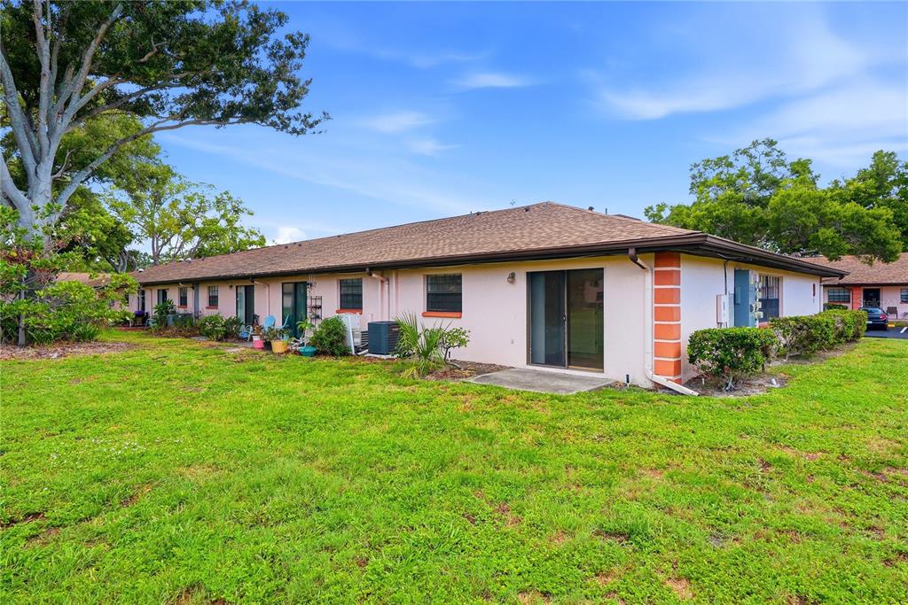 A single-story pink stucco apartment building with a brown shingled roof and sliding glass doors — 13250 RIDGE ROAD UNIT 9-1, LARGO, FL