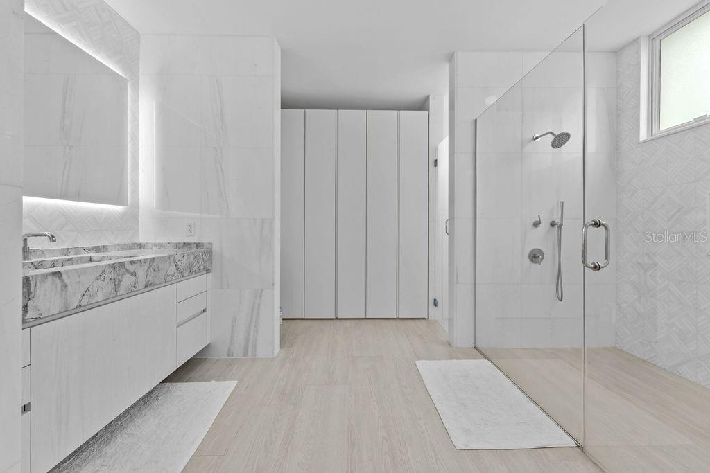 A modern bathroom features a marble vanity, a glass-enclosed walk-in shower, and light wood flooring — Ocean Sixteen 9000 RIO MAR BLVD UNIT 321, RIO GRANDE, PR