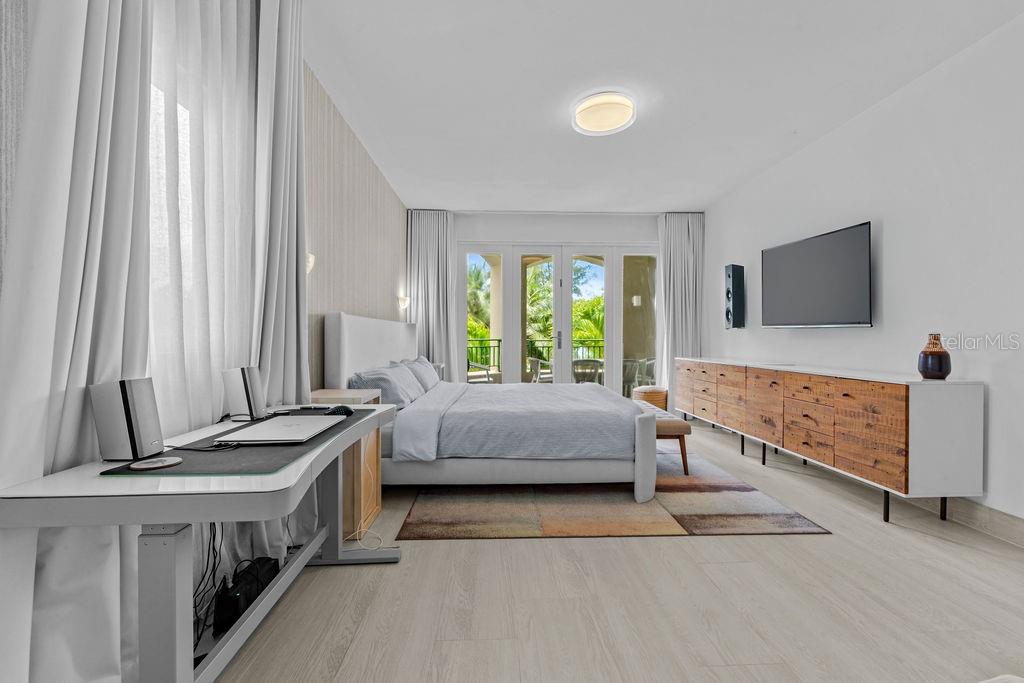 A modern bedroom features a bed, a desk, a long wooden dresser, and glass doors — Ocean Sixteen 9000 RIO MAR BLVD UNIT 321, RIO GRANDE, PR