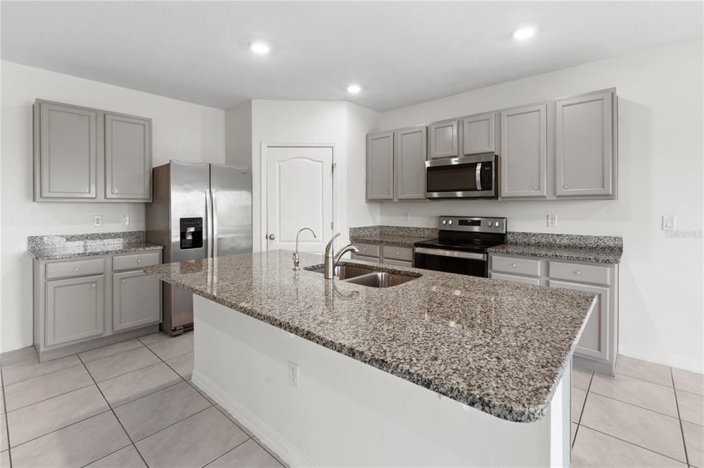 A kitchen with grey cabinets, granite countertops, a center island, and sliding glass doors — 2651 GRANDBURY GROVE ROAD, LAKELAND, FL