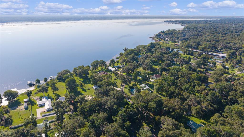 An aerial view shows houses nestled among trees along the shore of a large lake — 1975 E CR412 ROAD, LAKE PANASOFFKEE, FL