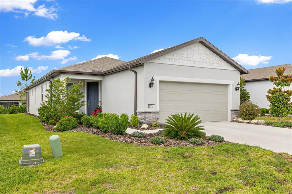 A single-story house with a light-colored stucco exterior, a two-car garage, and landscaped front yard — 8776 SW 58TH STREET ROAD, OCALA, FL