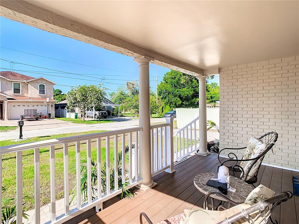 A covered front porch features white railings, two columns, and a view of the street — 3321 W AILEEN STREET, TAMPA, FL