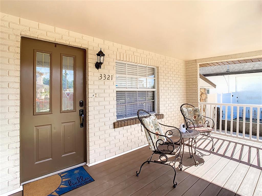 A covered front porch features a brown door, white brick walls, and two metal chairs — 3321 W AILEEN STREET, TAMPA, FL