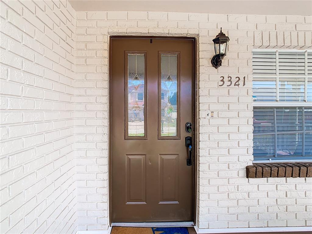 A brown front door with glass panels is set into a white painted brick wall — 3321 W AILEEN STREET, TAMPA, FL