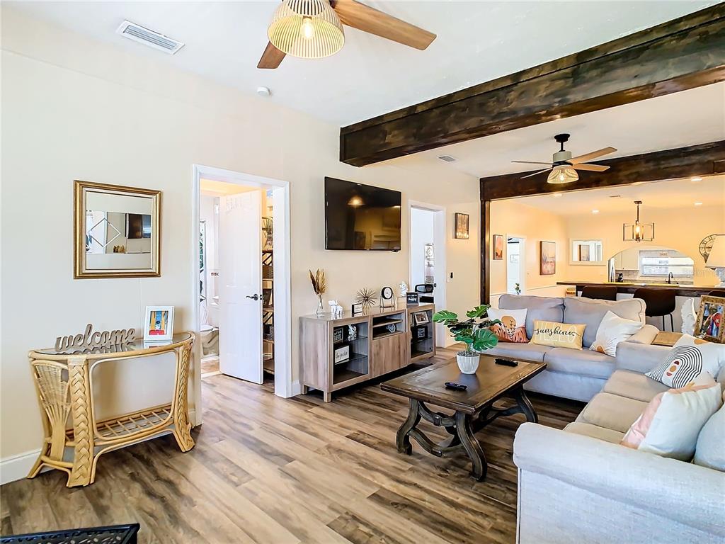 A living room features wood-look flooring, a ceiling fan, a television, and a wooden beam — 3321 W AILEEN STREET, TAMPA, FL