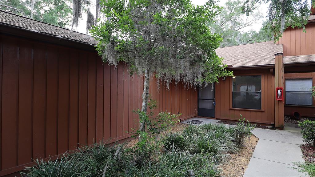 The exterior of a brown wood-sided house features a concrete walkway and a front door — 2701 NE 10TH STREET UNIT 708, OCALA, FL