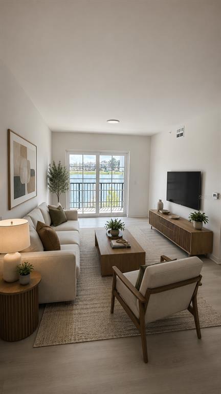 A living room features a sofa, armchair, coffee table, and a balcony overlooking a lake — 5579 MILLENIA PARK BOULEVARD UNIT 201, ORLANDO, FL