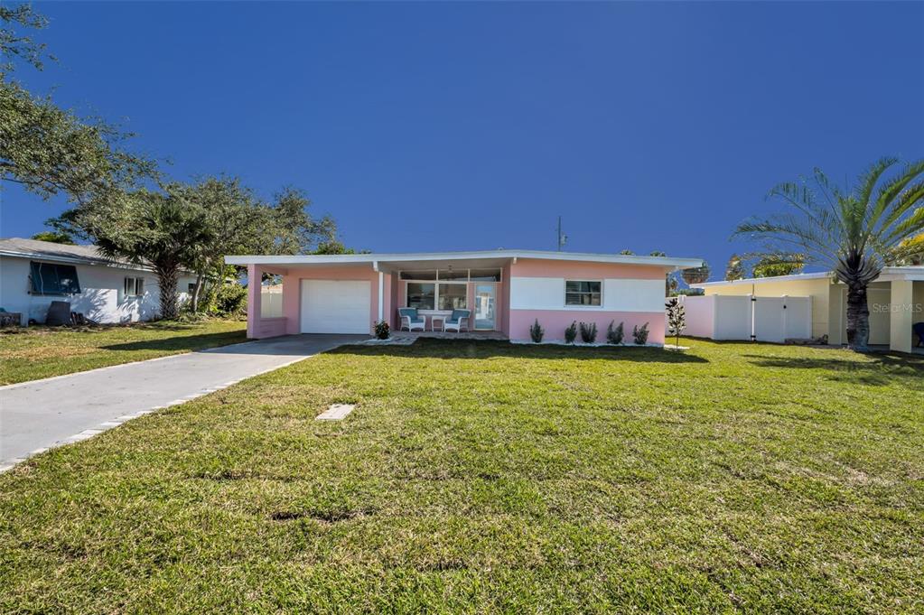 A single-story pink house with a white garage door and a large front lawn — 414 88TH AVENUE, ST PETE BEACH, FL