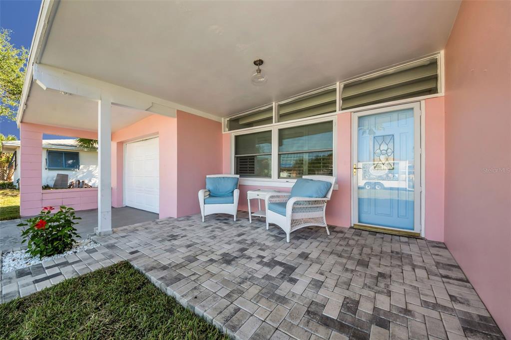 A pink house exterior features a paved front porch with two chairs and a door — 414 88TH AVENUE, ST PETE BEACH, FL