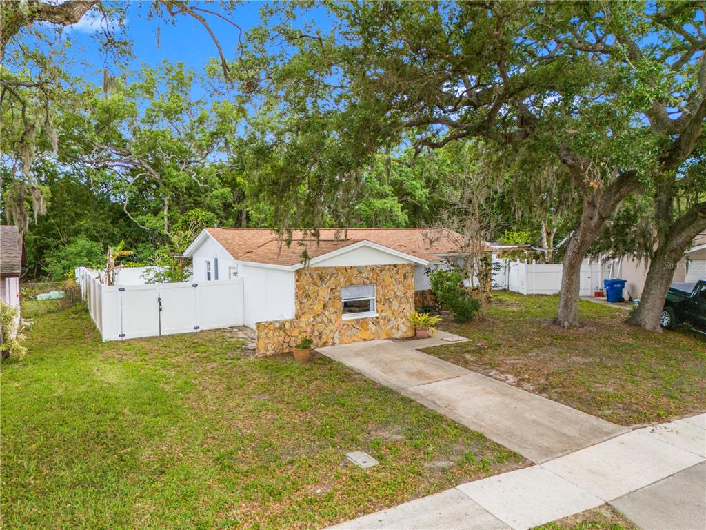 A single-story house with a stone facade, white siding, and a concrete driveway — 5638 146TH TERRACE N, CLEARWATER, FL
