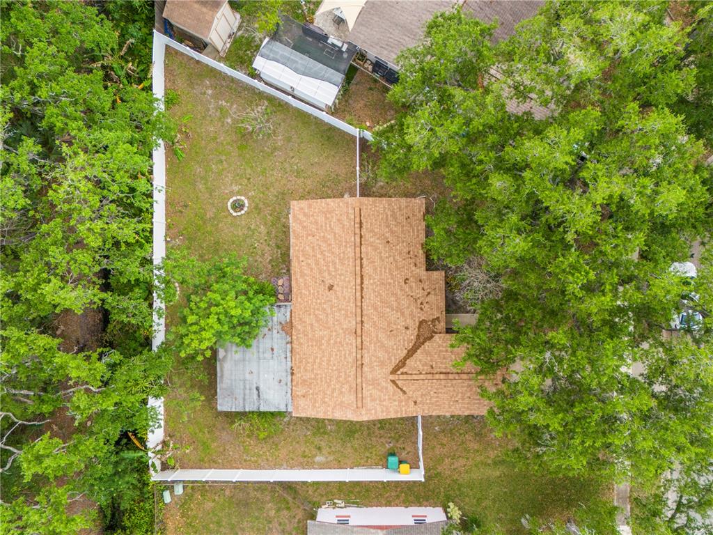 An aerial view shows a house with a brown shingled roof and a fenced backyard — 5638 146TH TERRACE N, CLEARWATER, FL