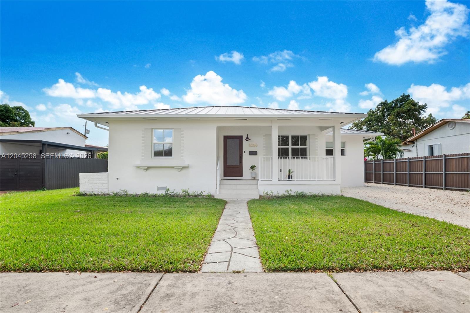 A white, single-story house with a metal roof and a front porch sits behind a lawn — 6356 SW 14th St, West Miami FL 33144, WEST MIAMI, FL
