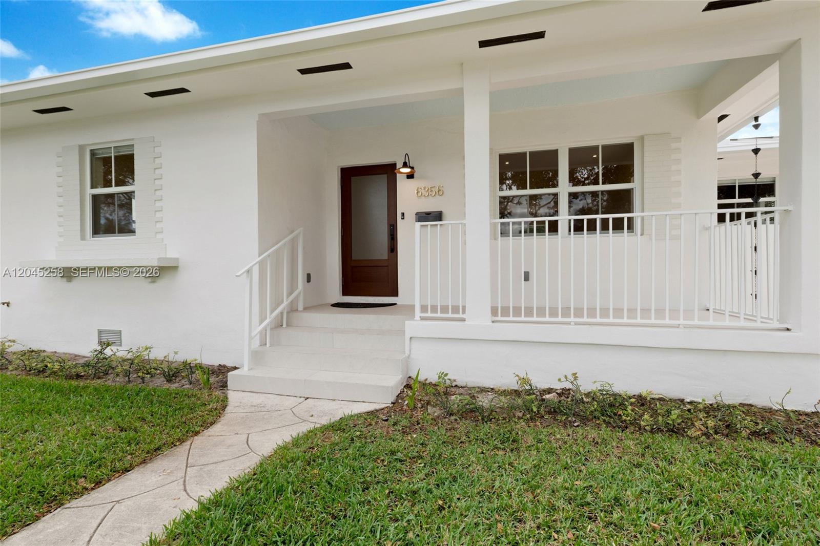 The exterior of a white house features a front porch, steps, and a wooden door — 6356 SW 14th St, West Miami FL 33144, WEST MIAMI, FL