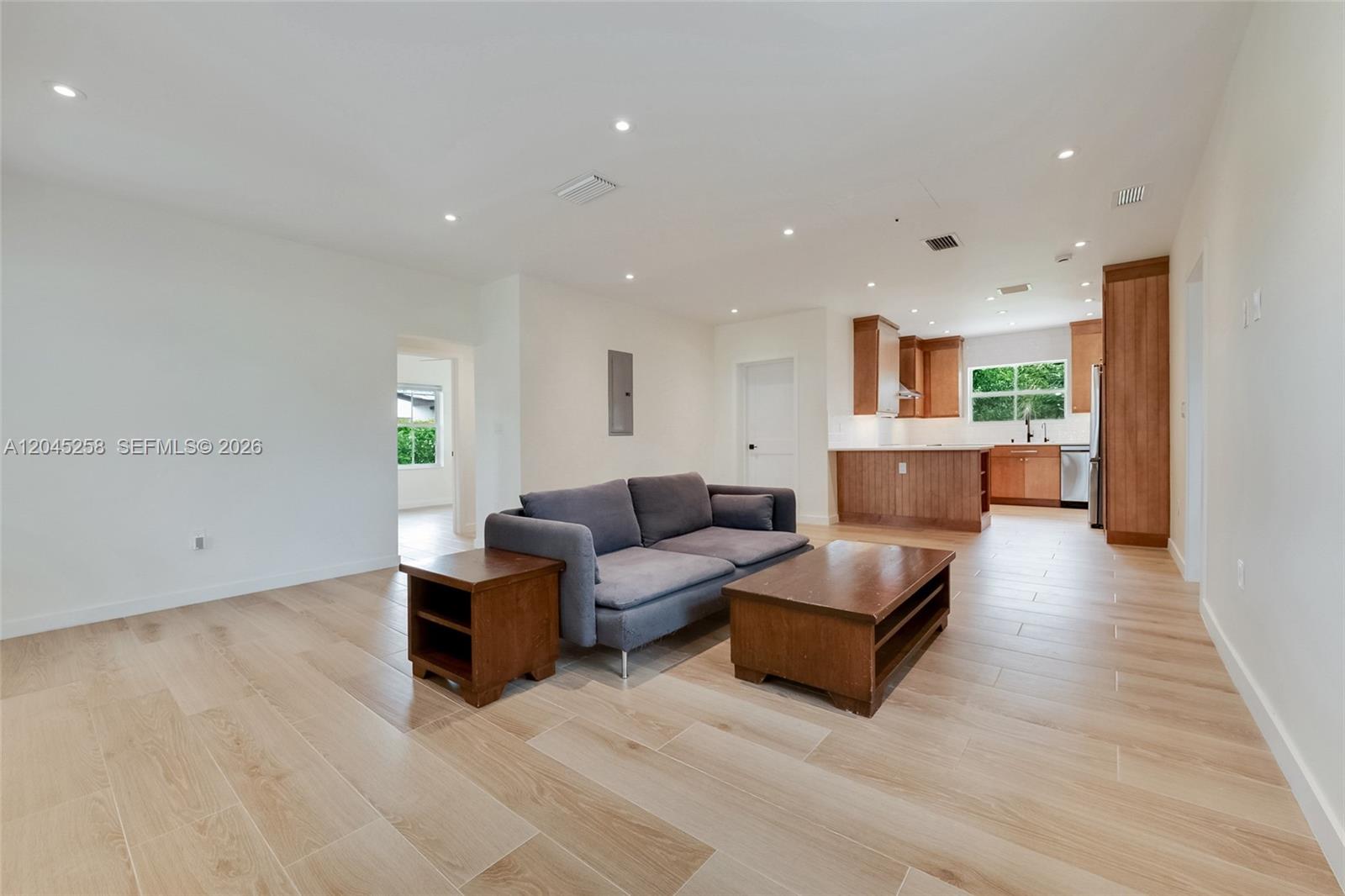 An open-concept living room features light wood-look tile flooring, a gray sofa, and a kitchen — 6356 SW 14th St, West Miami FL 33144, WEST MIAMI, FL