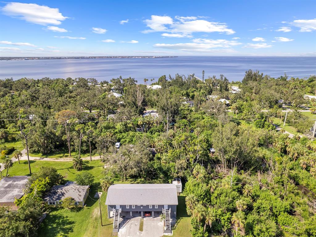 An aerial view shows a gray two-story house surrounded by dense trees near a bay — 23019 SENECA AVENUE UNIT B, PORT CHARLOTTE, FL